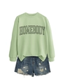 Detailed flat lay of a light green sweatshirt with black HOMEBODY lettering and denim shorts - Olive Green (Black Font)