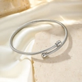 Silver twisted cable open bangle featuring polished double sphere ends on stone surface - Silver (F3550)