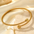 Golden cable style open bangle with spherical ends on a luxury silk and stone background - Gold (F3549)