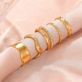 Set of 5 golden wave and beaded titanium steel rings displayed on pink silk fabric - Gold 5-Piece Set (C4421)