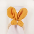 Detail of a bright yellow rabbit ear fabric napkin ring with a natural wooden base - Orange Bunny Ear Napkin Ring