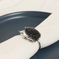 Detailed view of silver hedgehog napkin ring with intricate quills on white linen - Hedgehog Shape / Silver