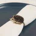 Vintage gold hedgehog napkin ring set on a navy blue plate with a white cloth napkin - Hedgehog Shape / Gold