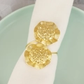 Elegant gold metal flower napkin rings with wavy edges on a white cloth and ceramic plate - Pleated Metal Flower Napkin Ring