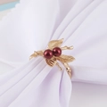 Detailed macro shot of golden leaf and red berry napkin ring on white fabric - Branch Red Berry Style