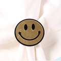 Servilletero dorado con cara sonriente y diseño de estrellas sobre tela blanca - Servilletero carita sonriente