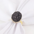 Détail macro du rond de serviette doré avec cristal noir ovale sur tissu blanc pur - Or Noir Druse