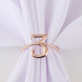 Detailed close-up of rose gold number 3 napkin ring on white fabric background - Number 3 / Rose Gold