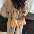 Borsa a tracolla in pelle cerata caramello indossata con un trench kaki - Marrone