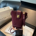 Burgundy suede bucket bag with leather trim and gold buckle shown held by hand - Burgundy