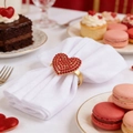 Detail of gold heart napkin ring with red rhinestones set in a romantic dessert scene - Gold