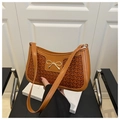 Detail of caramel woven texture on shoulder bag with golden bow metallic accent - Brown