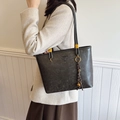 Dark gray tote bag with matte texture, gold hardware and bell charm on a model - With Pendant / Black
