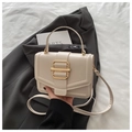 Détail du sac à main en cuir crème élégant avec boucle dorée sur fond de costume - Blanc