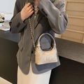 Sac à main matelassé beige avec poignée ronde et bandoulière chaîne porté par un modèle - Kaki