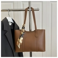 Detalle de un bolso tote marrón con un pañuelo de seda decorativo y textura de cuero - Tostado