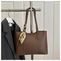 Detalle de bolso tote marrón oscuro con pañuelo de seda en un perchero de metal y puerta - Marrón Oscuro