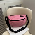 Sac bandoulière en nylon rose avec sangle réglable et étiquette mode sur une chaise blanche - Rose rosé