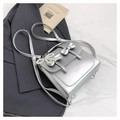 Détail du sac argenté métallisé avec doubles nœuds et breloque en perles sur fond stylé - Avec Pendentif / Argent