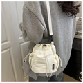 Detail of white drawstring bucket bag featuring a side pocket and black FASHION label - White