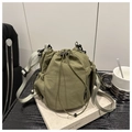 Close-up of olive green nylon drawstring bucket bag placed on a book prop on desk - Green