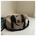 Beige Reisetasche mit schwarzen Gurten und abnehmbarem Schultergurt auf Bett - Khaki