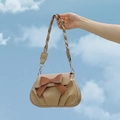 Beige crossbodytas met bruine strik en gevlochten riem tegen een helderblauwe luchtachtergrond - Khaki
