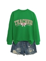 Detailed view of teacher sweatshirt with shamrock and bow print on green fabric - Grass Green