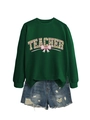 Detail of green sweatshirt with teacher text, clover pattern, and pink ribbon bow design - Dark Green