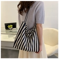 Detailansicht einer großen blau-weiß gestreiften Canvas-Tasche, getragen von einem Modell - Blau