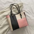 Bolso tote bicolor rosa y negro con correas ajustables sobre un blazer blanco - Rosa