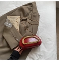 Detailed macro view of red patent leather clutch with a large gold U-shaped metal handle - Red