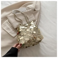 Detail der goldenen Pailletten-Beuteltasche mit Kettenriemen auf hellem Blazer-Hintergrund - Gold