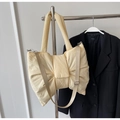 Close-up of light yellow bow-shaped quilted tote bag with smooth nylon texture - Off White