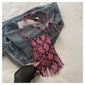 Macro detail of snakeskin pattern with long tassels and thin strap on a crossbody bag - Pink