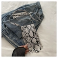Detail view of snakeskin print small crossbody bag featuring long fringes on denim background - White