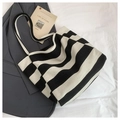 Vista dall'alto di una borsa tote in tela a righe con cartolina su lenzuola bianche - Nero