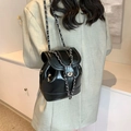 Glänzender schwarzer Lederrucksack mit Kettenriemen und silbernem Drehverschluss im Bucket-Stil - Schwarz