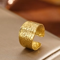 Primer plano de anillo ancho dorado en forma de C con textura martillada sobre satén - Textura de Lava Dorada (C6699)