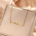 Detailopname van een vergulde mama-hanger aan een fijne ketting op zijden stof - Gouden Mama Stijl (F347) / Goud