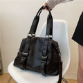 Bolso tote grande marrón oscuro con correas decorativas y hebillas plateadas en silla - Negro