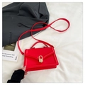 Elegante borsa a tracolla rossa con fibbia dorata su sfondo di biancheria da letto bianca - Rosso