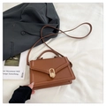Dettaglio borsa in pelle marrone con chiusura girevole dorata su tessuto bianco pieghettato - Marrone