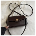 Detail of dark brown patent leather shoulder bag featuring a gold ring twist lock - Dark Brown