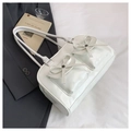 Detail view of white Boston bag featuring dual front pockets and bow accents on fabric - White