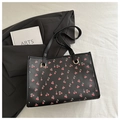 Close-up of a floral tote bag with cherry print and metallic eyelets on white fabric - Black