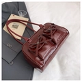 Close-up of deep red glossy Boston bag with dual pockets and delicate bow detail - Red