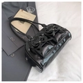 Detail of glossy black Boston bag with leather bows on light gray background - Black