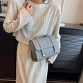 Minimalist grey pebble leather crossbody bag with silver buckle on elegant model - Gray