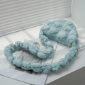 Light blue bubble quilted crossbody bag with puffy pleated strap on a bright windowsill - Light Blue